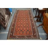 A Persian carpet, rust ground with geometric design.