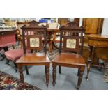 A pair of Victorian mahogany hall chairs with tile inset back panel.