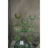 Two etched pale green glass wine glasses and three other glasses.