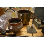 An eastern embossed copper pot, an engraved brass pot and a candle stand.