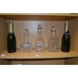 Three cut glass decanters and two bottles of champagne.