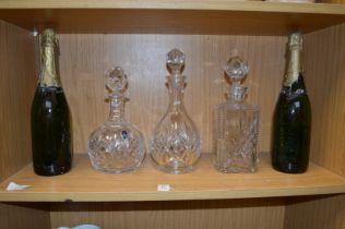 Three cut glass decanters and two bottles of champagne.
