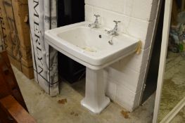 A Victorian style porcelain pedestal sink with chrome taps.