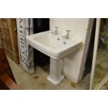 A Victorian style porcelain pedestal sink with chrome taps.