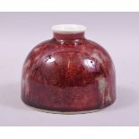 A CHINESE RED GLAZED PORCELAIN INKWELL / VASE, base with six character mark, 12cm diameter.