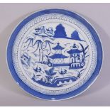 A LARGE CHINESE BLUE AND WHITE PORCELAIN DISH, decorated with buildings, trees and boats, 30.5cm