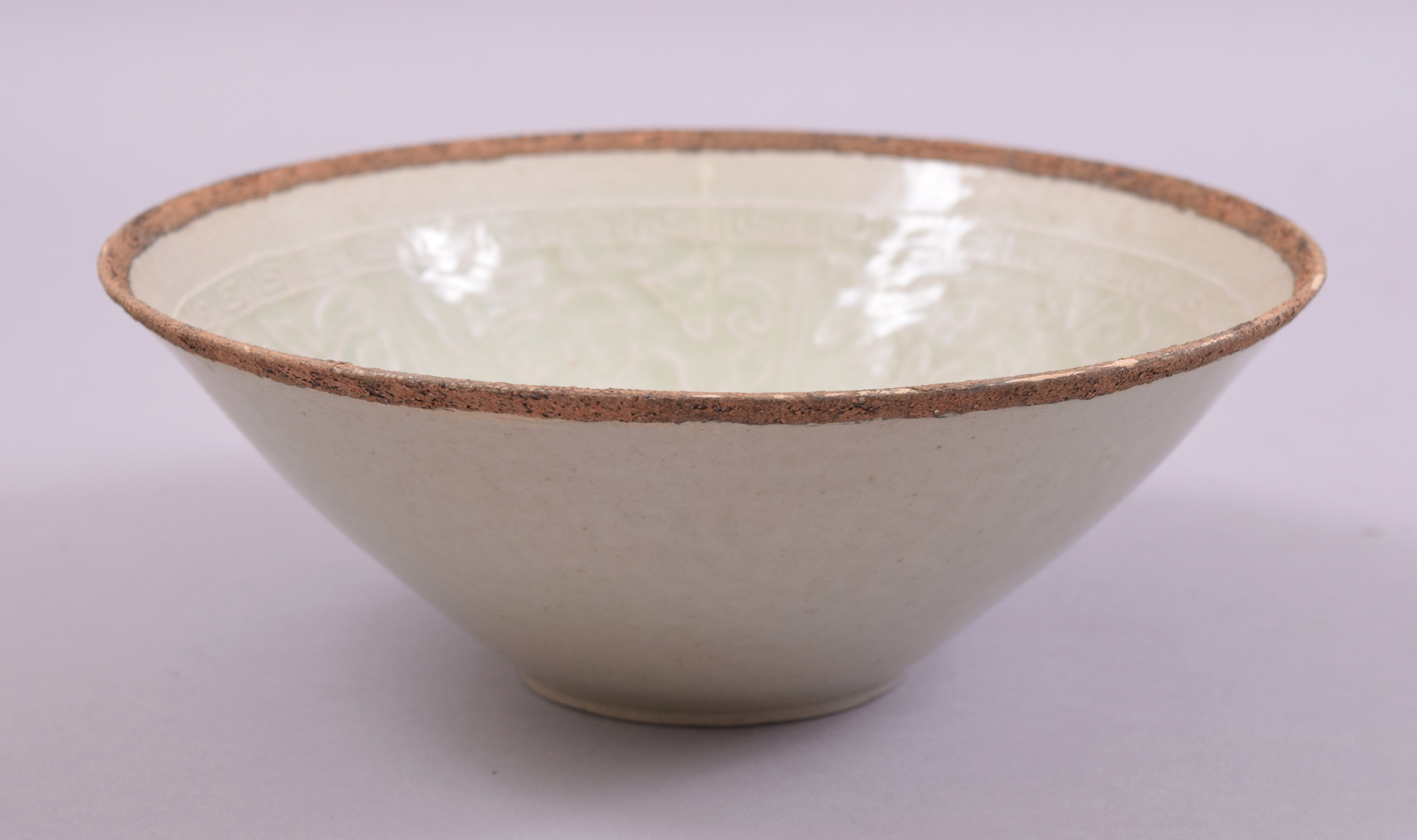 A CHINESE CELEDON GLAZED INCISED BOWL, the interior with carved floral decoration, 19.5cm diameter.