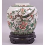 A GOOD CHINESE FAMILLE VERTE PORCELAIN JAR AND HARDWOOD STAND, painted with a peacock amongst native