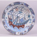 A LARGE IZNIK GLAZED POTTERY DISH, painted with a ship and waves with stylised fish, 31cm diameter.