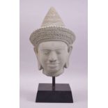 A DECORATIVE 20TH CENTURY THAI CARVED HARDSTONE HEAD, of a man wearing a traditional hat, mounted on