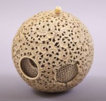 A CARVED AND PIERCED IVORY PUZZLE BALL, profusely pierced and carved with foliate design, approx.