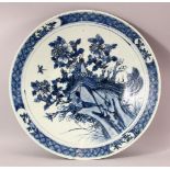 A LARGE CHINESE BLUE AND WHITE PORCELAIN CHARGER, central depicting a peacock amongst native