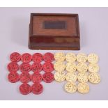 A SET OF FOURTEEN CHINESE CANTON PIERCED IVORY RED AND WHITE STAINED COUNTERS, 3cm diameter,