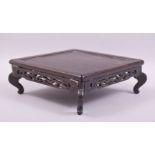 A CHINESE SQUARE FORM WOODEN STAND, supported on four curving legs, 20.5cm square, (af).