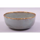 A CHINESE RU WARE PETAL SHAPE BOWL, with gilt rim and calligraphy to base, 18cm diameter.