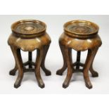 A PAIR OF CHINESE OAK CIRCULAR STANDS with turned, dished tops, supported on five curving legs