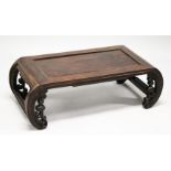 A CHINESE ROSEWOOD LOW TABLE WITH PANELLED TOP, supported on curving ends with pierced and carved