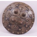 AN INDIAN EMBOSSED LEATHER AND COPPER STUDDED SMALL HAND SHIELD, the copper work with engraved