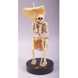 A SUPERB JAPANESE CARVED IVORY OKIMONO OF A SKELETON, fitted to a circular wooden stand, the