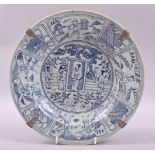 A CHINESE BLUE AND WHITE PORCELAIN DISH, painted with panels figures and objects, 29.5cm diameter.