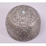AN INDIAN WHITE METAL DOME SHAPED BOX, with hinged cover, repouse decorated, inset with a