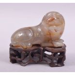 A CHINESE AGATE FIGURE OF A LION DOG, on a fitted wooden stand, figure 8cm long.