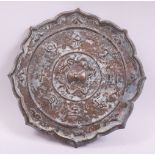 A CHINESE BRONZE PETAL FORM MIRROR, with raised decoration of characters, chilong and stylised
