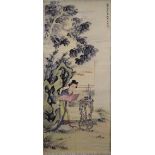 A CHINESE SCROLL PAINTING OF A FEMALE FIGURE, in a garden setting next to a root wood table with