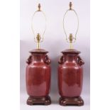 A GOOD LARGE PAIR OF CHINESE SANG DE BOEUF TWIN HANDLE LAMP VASES, the handles formed in the shape