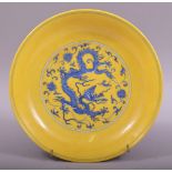 A CHINESE YELLOW GROUND PORCELAIN DRAGON DISH, the centre painted in blue with a roundel