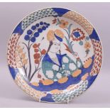 A PERSIAN IRANIAN GLAZED POTTERY DISH, centre painted with a figure holding a flower, 30cm