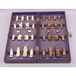 A CHINESE CARVED AND STAINED IVORY FIGURAL CHESS SET, housed in a folding chess board.