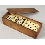 A SET OF EBONY AND BONE DOMINOES in a box. 1.875ins long.