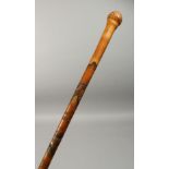 A CHINESE ENGRAVED AND CARVED BAMBOO WALKING CANE, with mountain, buildings, figures and caligraphy.