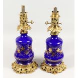 A GOOD PAIR OF 19TH CENTURY BLUE GLASS AND GILT METAL LAMPS decorated in gilt with fruiting vines.