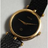 A GUCCI BLACK FACED WRIST WATCH with leather strap.