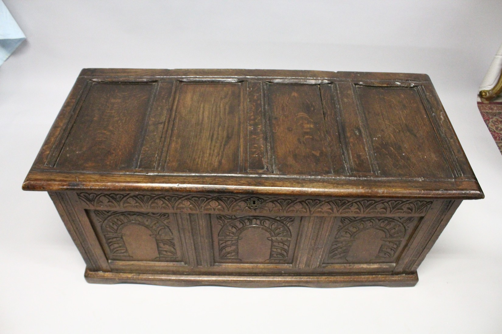 AN 18TH CENTURY OAK COFFER with a panelled top and triple panelled front, carved with arches. 4ft - Image 3 of 4
