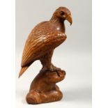 A GOOD CARVED WOOD EAGLE standing on a rock, 14ins high.