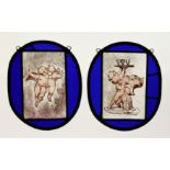 A PAIR OF OVAL BLUE GLASS LEADED LIGHTS decorated with cupids. 9.5ins x 8ins