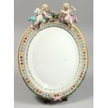 A GOOD MEISSEN OVAL MIRROR with two cupids. Cross swords mark in blue.