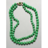 A GOOD TWO ROW JADE NECKLACE with gold clasp.