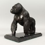 A BRONZE GORILLA on a marble base, 6ins long.