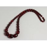 A RED AMBER FIFTY BEAD NECKLACE.