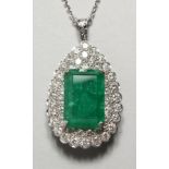 A SUPERB 18CT WHITE GOLD PENDANT set with a large emerald surrounded by a diamond.