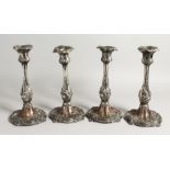 A SET OF FOUR ROCCOCO STYLE PLATED CANDLESTICKS. 10ins high.