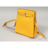 A YELLOW LEATHER BAG with gilt lock and long strap. 7ins x9.5ins.