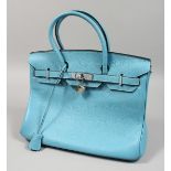 A LIGHT BLUE LEATHER BAG with chrome lock. 13ins x11.5ins. with dust cover.