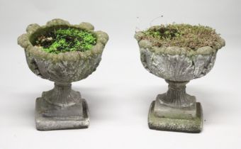 A PAIR OF WEATHERED COMPOSITE GARDEN URNS on pedestal bases. 21ins high x 19 ins diameter.