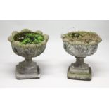 A PAIR OF WEATHERED COMPOSITE GARDEN URNS on pedestal bases. 21ins high x 19 ins diameter.
