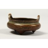 A SMALL CHINESE BRONZE CIRCULAR CENSER with handles, impressed mark, 2ins diameter.